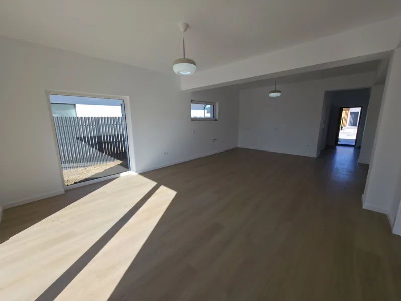 Living luminos cu fereastră mare și holul în fundal, finisaje standard